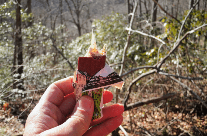 hand holding a protein bar on a hiking trail